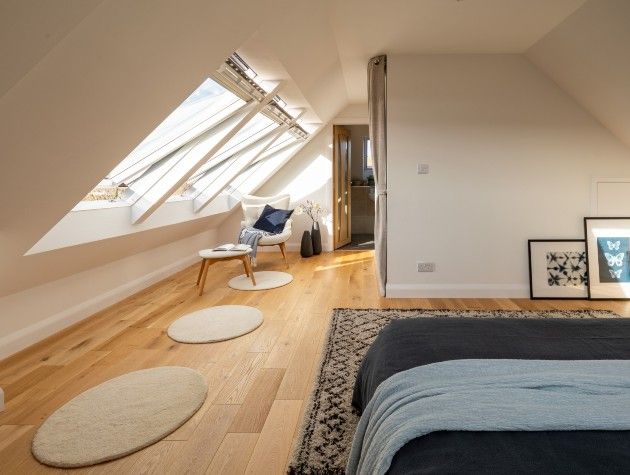 converted loft bedroom with rugs and open velux windows