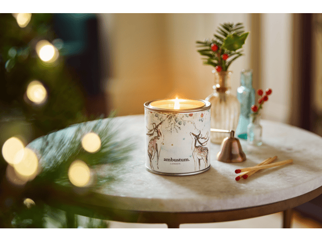 Reindeer Noel candle tin with Christmas tree in the background