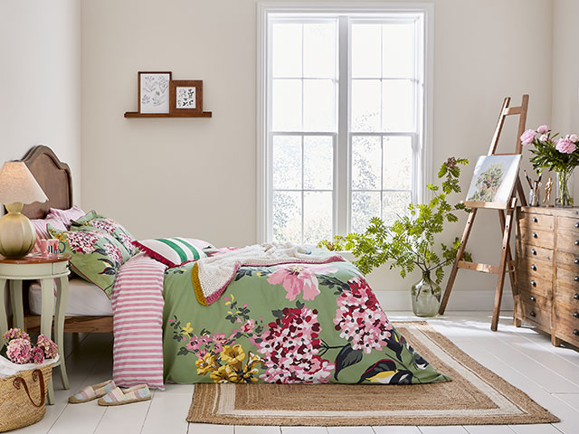 Summer green bedspread in bedroom with plants and wooden furniture