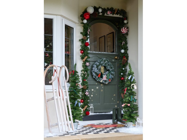 Decorated door for Christmas with garland, mini trees, wreath and sleigh