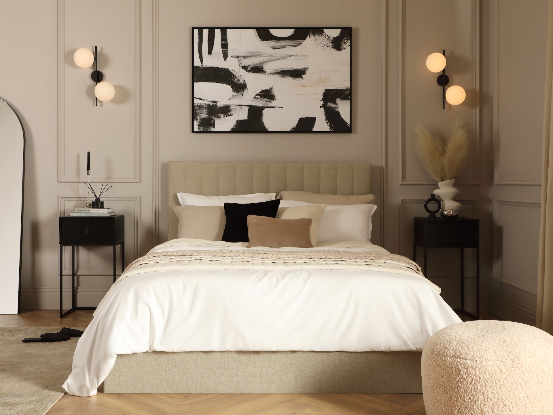 Off white and black monochrome bedroom with white sheets and boucle pouffe