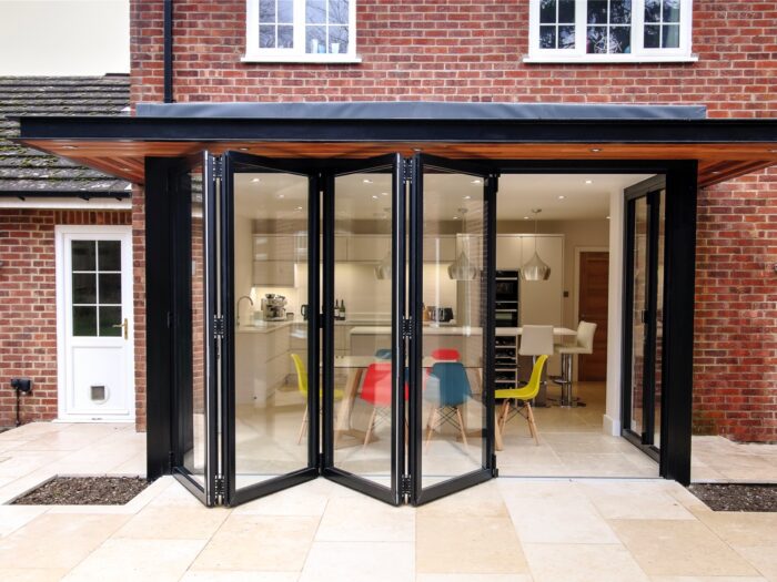 Exterior of house with black bi-fold windows looking through to kitchen diner