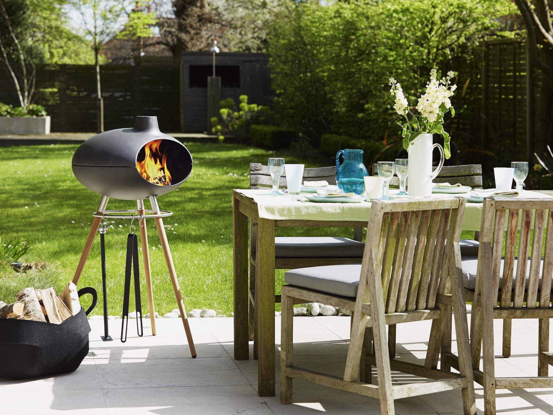 Forno Grill 2 by Morso next to wooden outdoor table and chair set