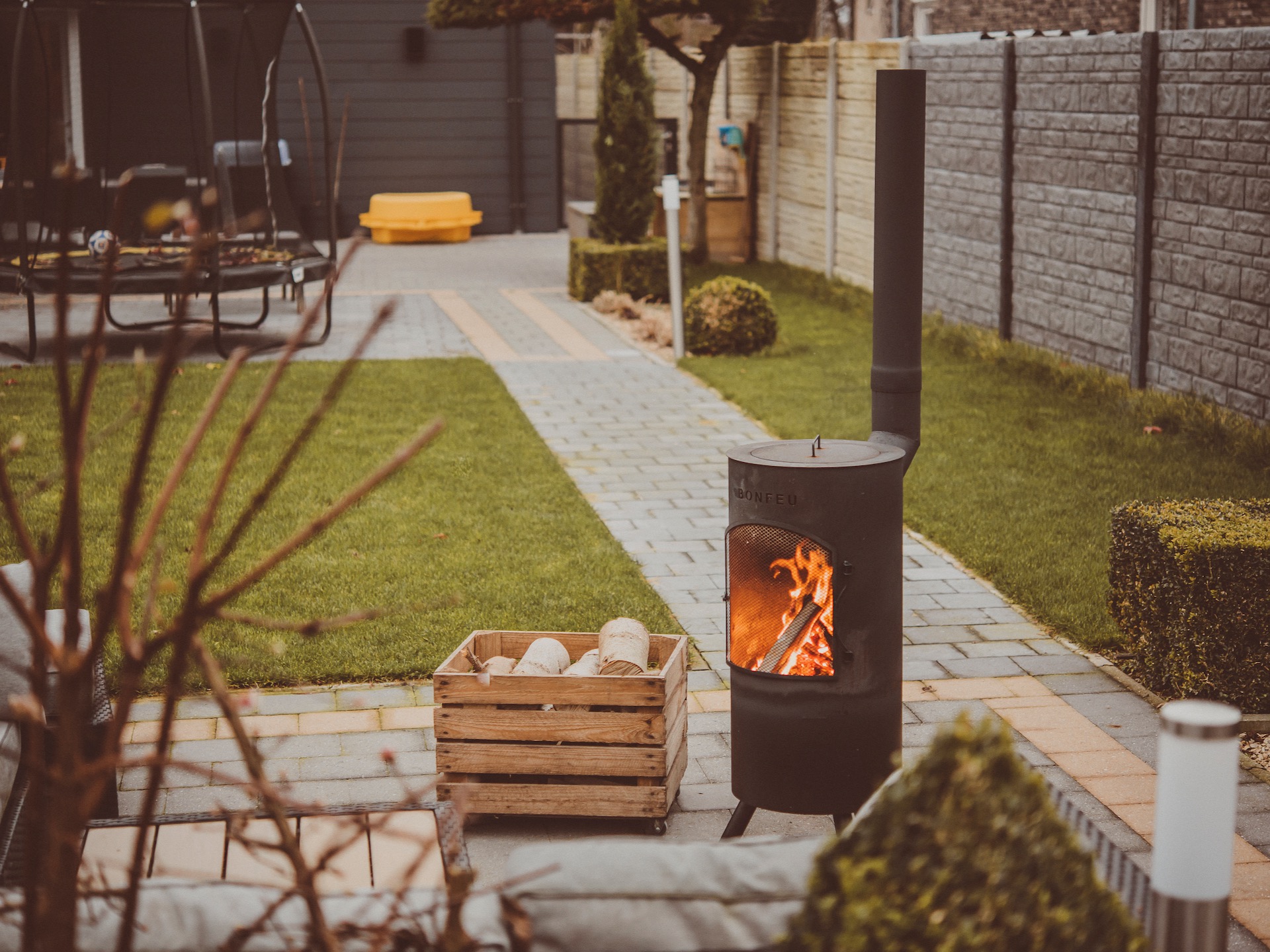 Outdoor wood burner on patio with lawn beyond