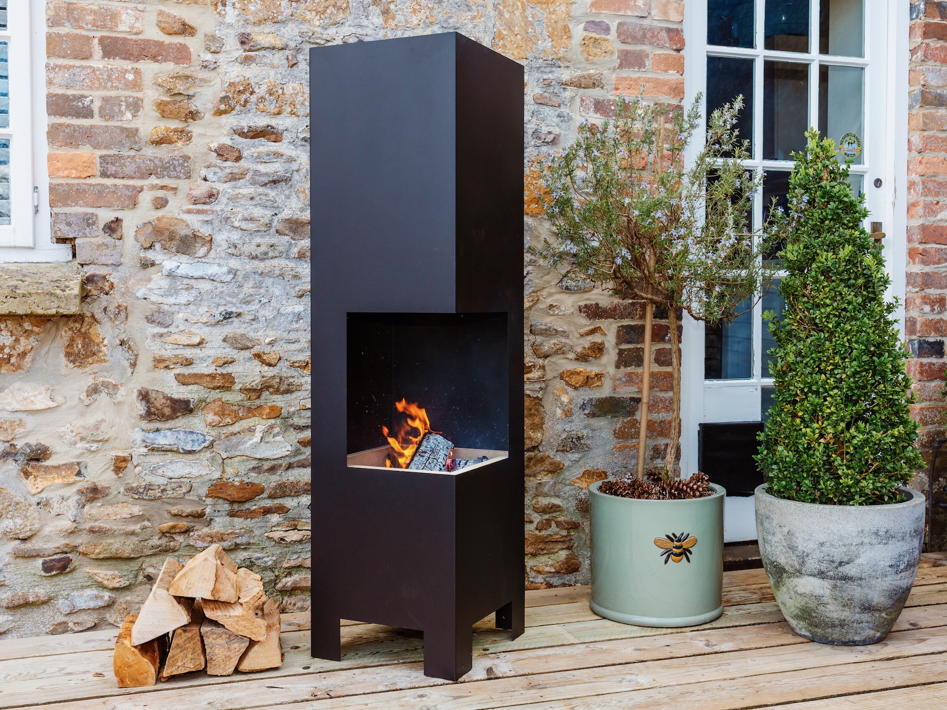 Contemporary box fire pit next to exterior brick wall