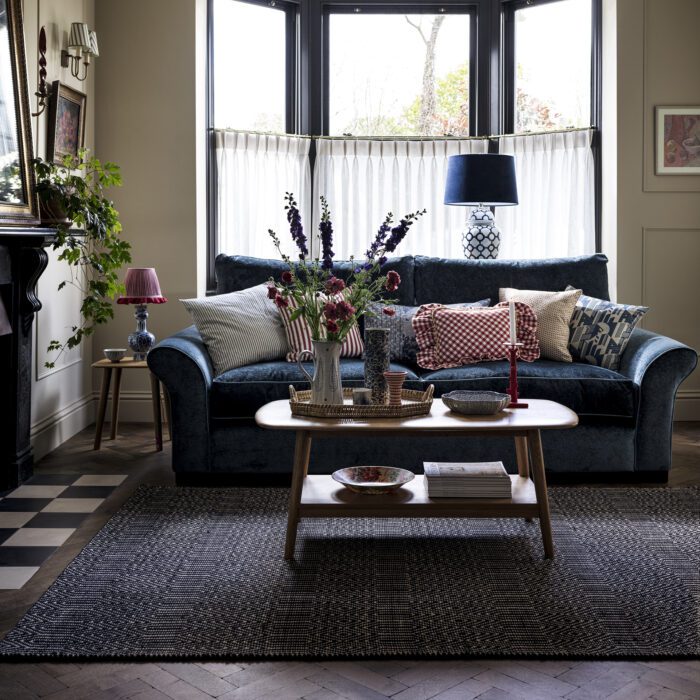 Living room with a large black rug underneath the sofa and coffee table