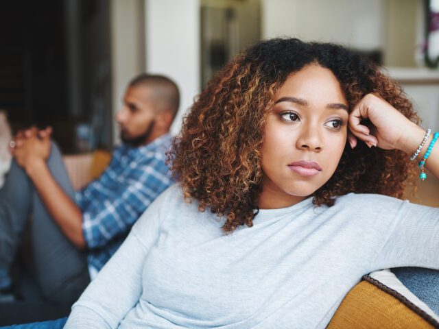 A couple on a sofa looking in opposite directions after a fight