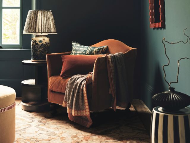 Masculine snug with green walls and an orange chair